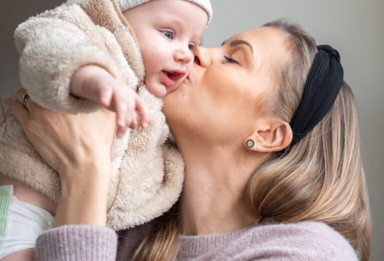 A woman kisses a baby on the cheek.